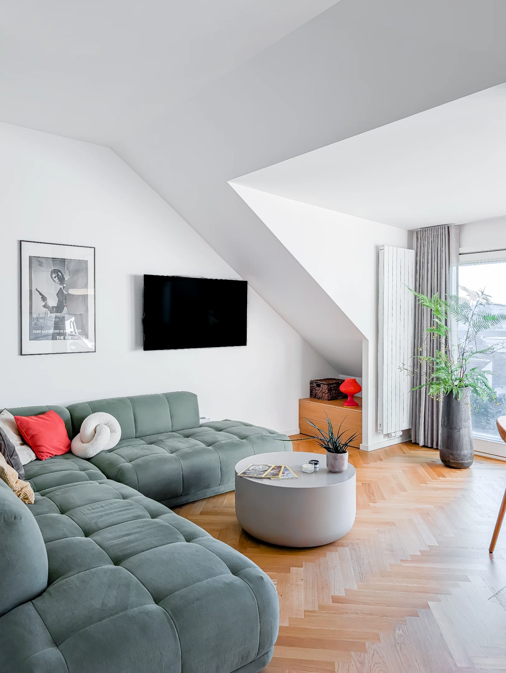 Moderní obývací pokoj s šedou sedačkou a parketami.